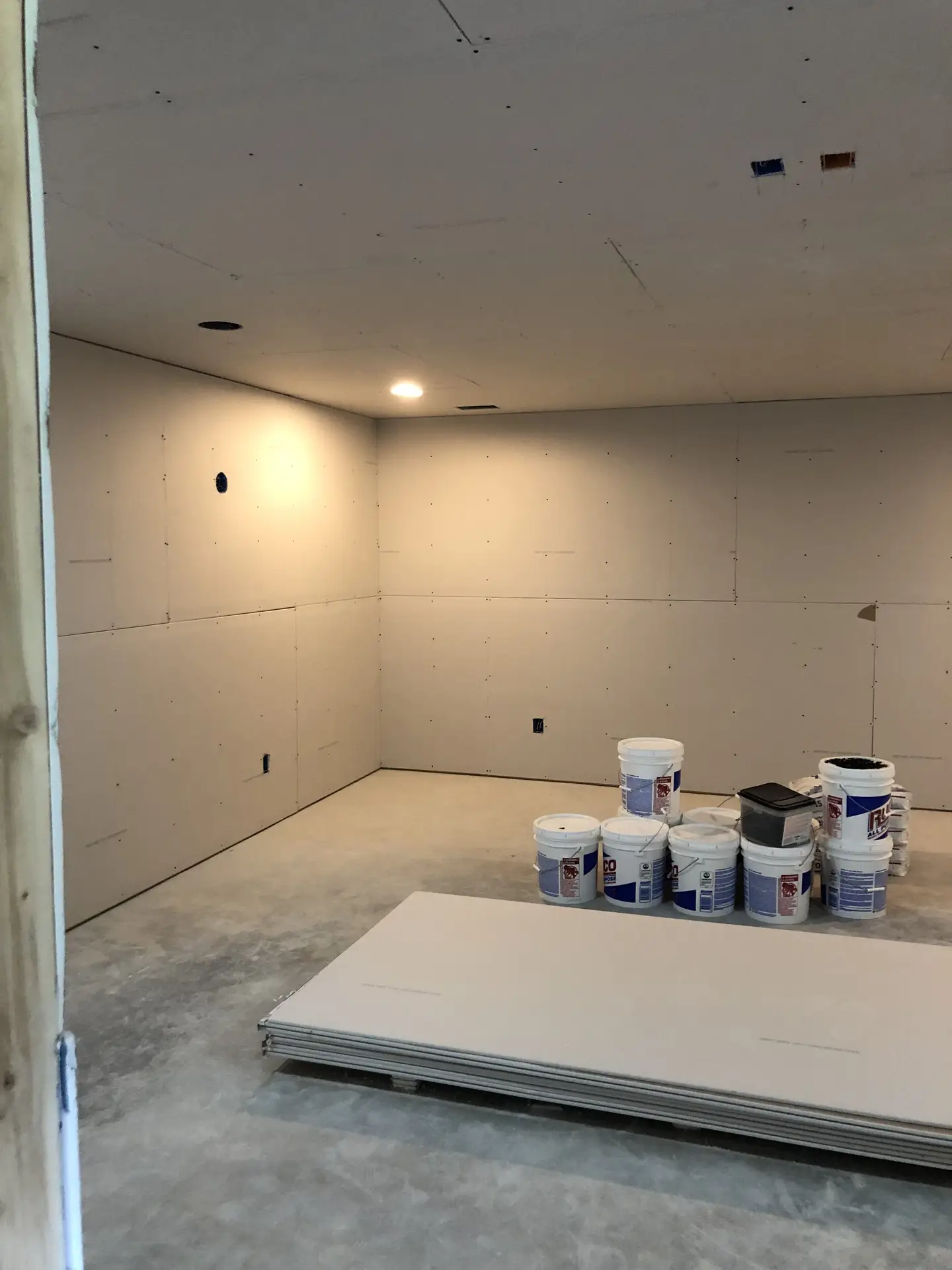 Unfinished basement during build out with framed walls and drywall preparation