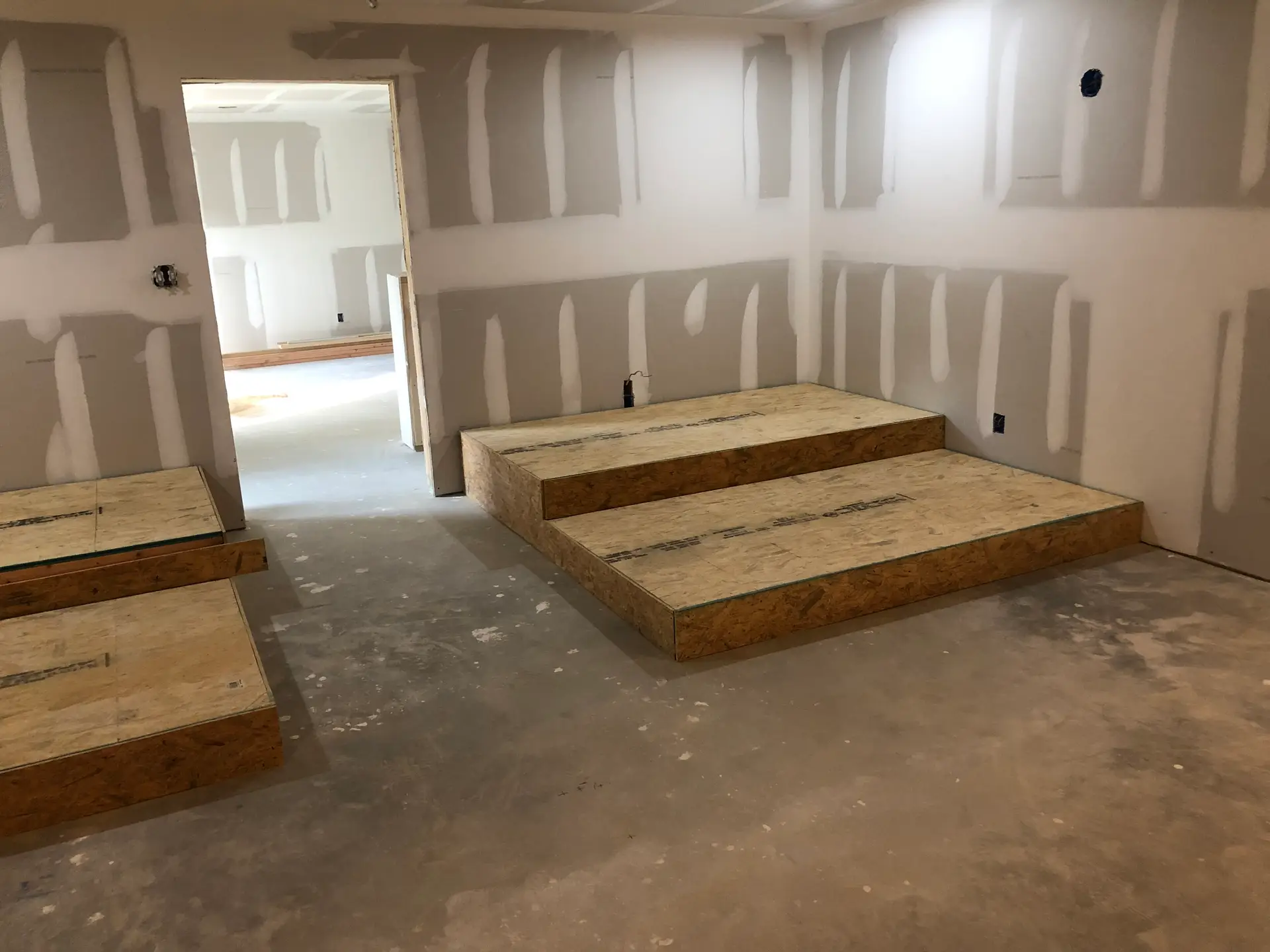 Basement build out in progress with framed platform and unfinished drywall