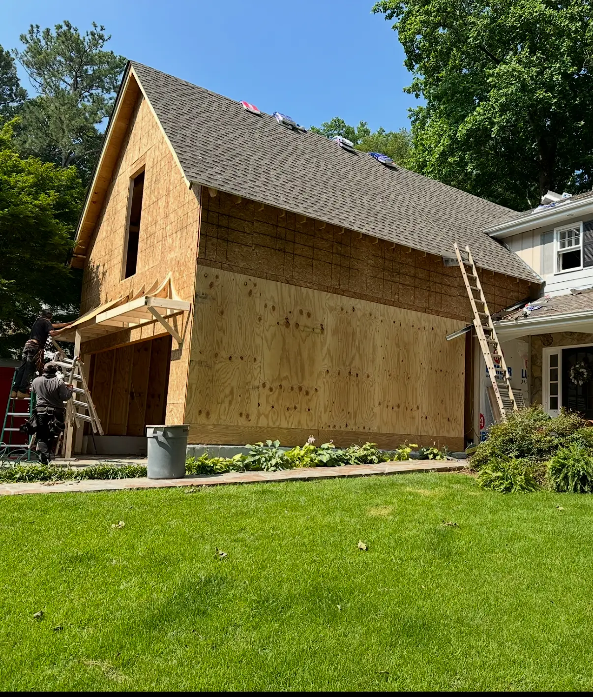Exterior garage addition framed and dried in with roofing shingles installed for master bathroom and walk - in closet