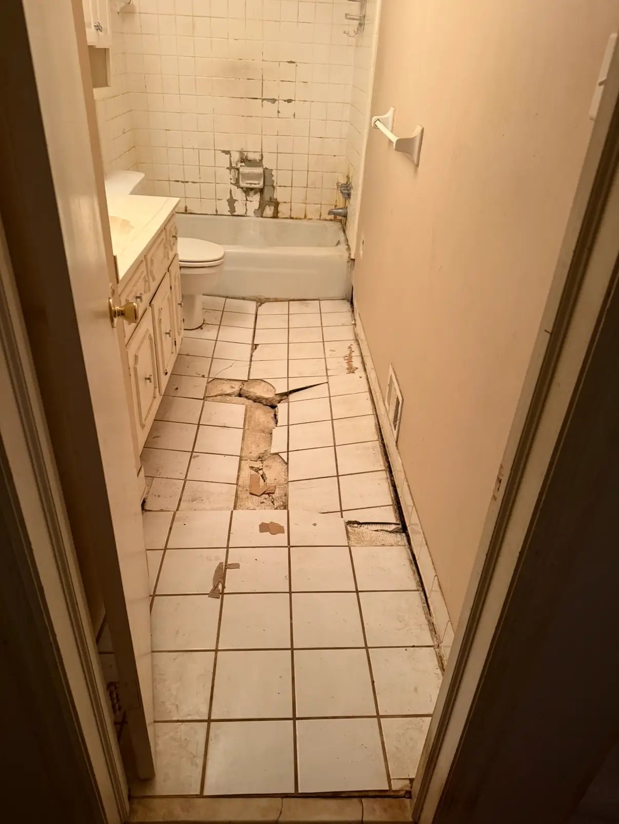 Bathroom with sunken and damaged flooring before renovation