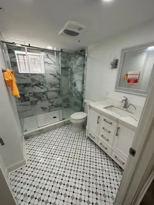 Finished basement bathroom with tiled shower, patterned til flooring, and large vanity