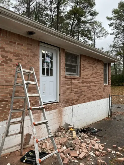 Exterior home renovation with updated entryway and foundation work on brick house